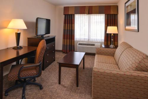 a hotel room with a desk and a couch and a television at Holiday Inn Express & Suites Bridgeport by IHG in Bridgeport