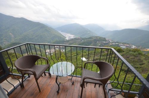 two chairs and a table on a balcony with mountains at Cingjing Four Seasons B&B in Renai