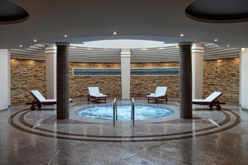 a lobby with chairs and a pool in the middle at Alkyon Resort Hotel & Spa in Vrahati