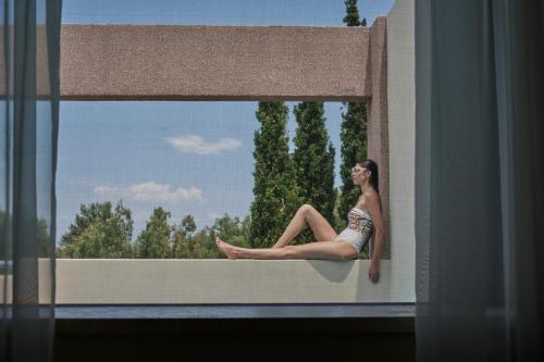 a woman sitting on the ledge of a window at Alkyon Resort Hotel & Spa in Vrahati