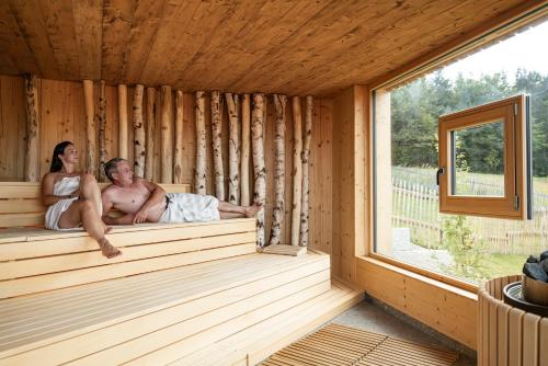 a man and a woman sitting in a sauna at Hunderesort Waldeck - 4 Sterne Urlaub mit Hund in Philippsreut