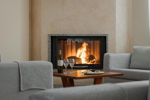 a living room with a fireplace with wine glasses on a table at Alkyon Resort Hotel & Spa in Vrahati