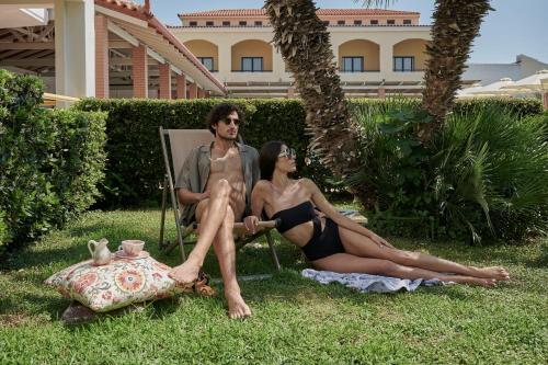 a man and a woman sitting in a chair in the grass at Alkyon Resort Hotel & Spa in Vrahati