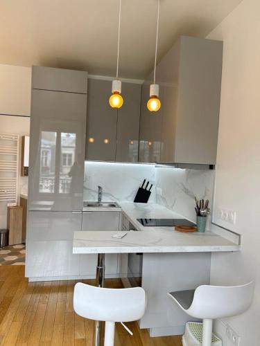 une cuisine blanche avec deux tabourets blancs et un comptoir dans l'établissement Spacious apartment near Eiffel Grenelle F2, à Paris