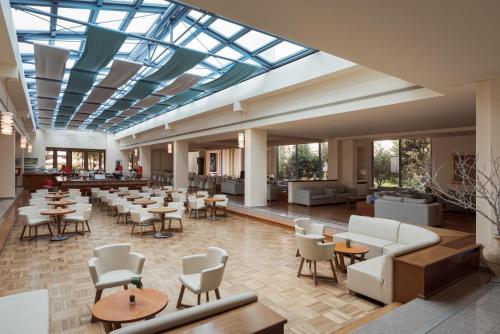 a large lobby with tables and chairs and a large glass ceiling at Alkyon Resort Hotel & Spa in Vrahati