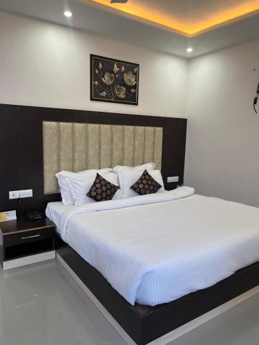 a bedroom with a large bed with white sheets and pillows at Aliza Inn And Suites By SRS Hotels in Dharamshala