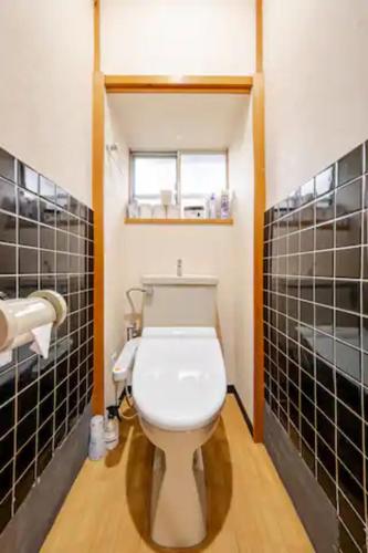 a bathroom with a toilet with black tiled walls at Kanazawa-Hachitabi Sennichi in Kanazawa