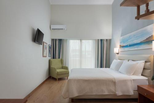 a hotel room with a bed and a green chair at Alkyon Resort Hotel & Spa in Vrahati