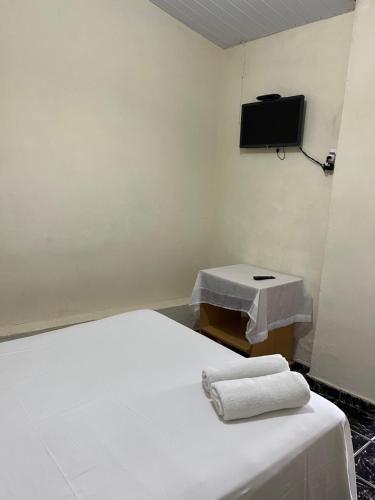 a room with a bed and a tv on the wall at Suítes São Judas in Pirenópolis