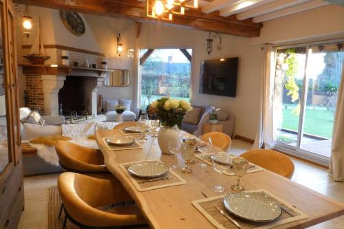 une table à manger avec des verres à vin et un salon dans l'établissement Maisons Normande à 5 minutes de Deauville, à Bonneville-sur-Touques
