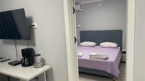 a bedroom with a bed with purple sheets and a television at Yassy hotel, Turkistan in Türkistan