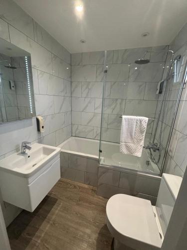 a bathroom with a tub and a toilet and a sink at Holtwhites Hotel in Enfield