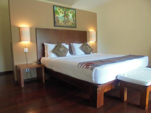 a hotel room with a large bed with two tables at Biyukukung Suite & Spa in Ubud