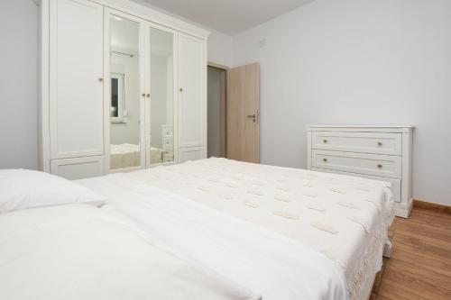 a white bedroom with a large bed and a dresser at Relax 1 in Pakoštane