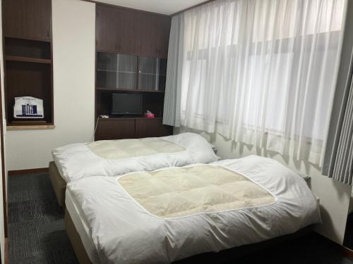 two beds in a hotel room with a window at Marina Bay Atami in Atami