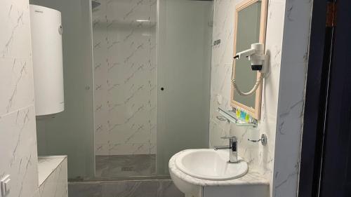 a white bathroom with a sink and a shower at Yassy hotel, Turkistan in Türkistan