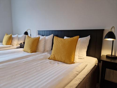 a bedroom with two beds with yellow and white pillows at Hotell Erikslund in Ängelholm