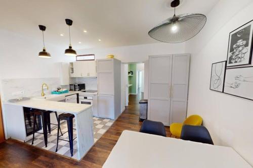 une cuisine avec des armoires blanches et une table et des chaises dans l'établissement F5 - Rousseau, au Havre