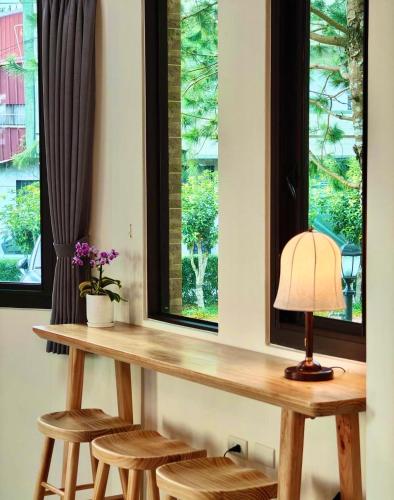 a table with stools and a lamp in front of a window at Green Castle in Ch'ieh-tung-chiao