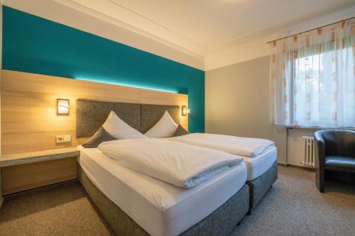 a bedroom with a large bed and a blue wall at BurgStadt-Hotel in Kastellaun