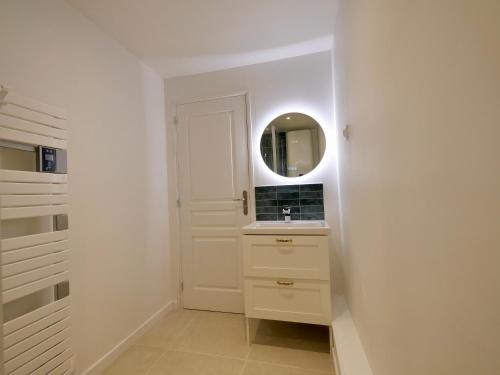a white bathroom with a sink and a mirror at D-Day Suites in Carentan