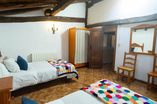 a bedroom with two beds and a chair and a mirror at Pagorriaga in Beasain