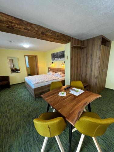 a hotel room with a bed and a wooden table and chairs at Landhaus Brodack in Alt Zauche