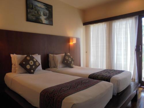 a hotel room with two beds and a window at Biyukukung Suite & Spa in Ubud
