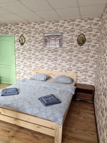 a bedroom with a wooden bed in a brick wall at Apartament Erfolg 11 in Daugavpils