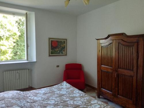 a bedroom with a bed and a red chair at Villa Gildanna2 in Orio Litta
