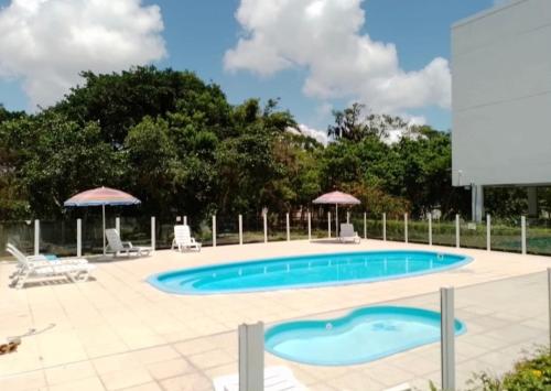 a swimming pool in a yard with chairs and umbrellas at Praia da Cachoeira in Florianópolis