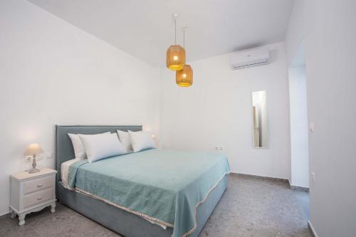 a bedroom with a bed with a blue blanket and a lamp at Villa Kalathos Dream White in Kalathos