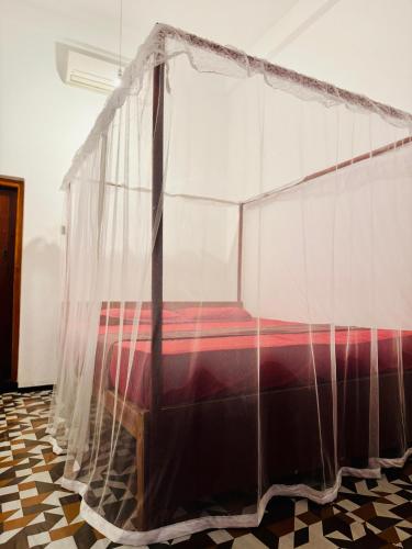 a bed covered in mosquito nets in a room at Cozy Sand Beach Hotel in Arugam Bay