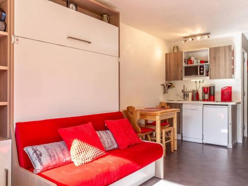 un salon avec un canapé rouge et une cuisine dans l'établissement Studio rénové à Plagne Centre, accès direct pistes de ski, balcon, parking gratuit - FR-1-351-79, à La Plagne