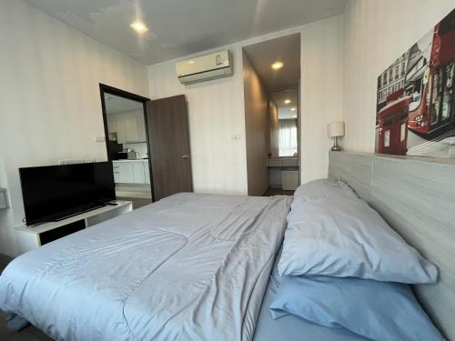 a bedroom with a bed and a flat screen tv at The Prio Condo Chiang Mai in Chiang Mai
