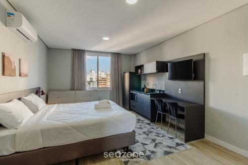a bedroom with a bed and a desk with a computer at TCO - Apartamentos no Centro Histórico Porto Alegre/RS in Porto Alegre