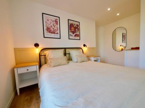 a bedroom with a large white bed with two night stands at D-Day Suites in Carentan