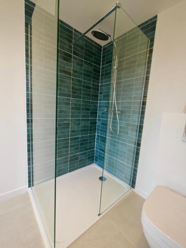 a shower with a glass door in a bathroom at D-Day Suites in Carentan