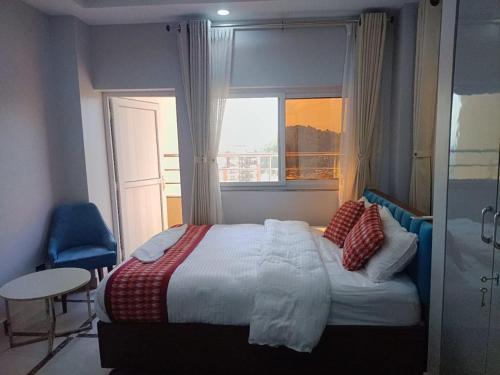 a bedroom with a bed and a window and a table at Buigal Bagan Restaurent & Apartment in Burhānilkantha