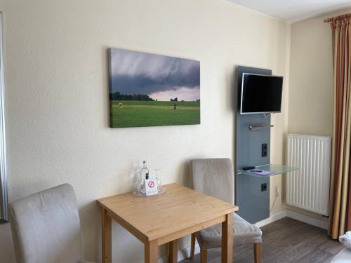 a room with a table and chairs and a television at Hotel Deichvoigt in Cuxhaven