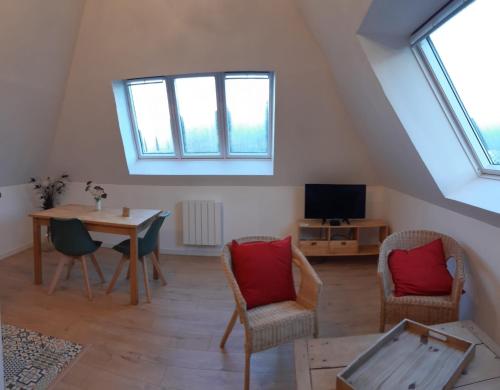 un salon avec une table, des chaises et une télévision dans l'établissement La Charretterie Cœur du village typique Normand, à Saint-Christophe-sur-Condé