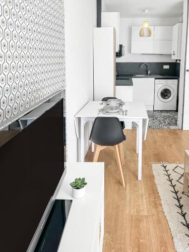 - une cuisine blanche avec une table et une chaise dans l'établissement Appartement lumineux, Wi-Fi et parking privé, à Niort