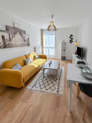 un salon avec un canapé jaune et une table dans l'établissement Appartement lumineux, Wi-Fi et parking privé, à Niort