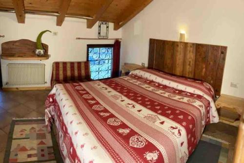 a bedroom with a large bed with a red blanket at Chalet Rustico Bertolini per Gruppi! in Vermiglio