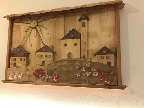 a wooden picture of houses and flowers on a wall at Chalet Rustico Bertolini per Gruppi! in Vermiglio
