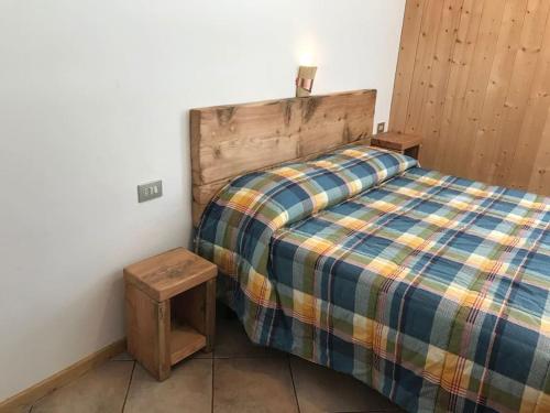 a bedroom with a bed with a wooden head board at Chalet Rustico Bertolini per Gruppi! in Vermiglio