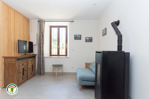 a living room with a black refrigerator and a couch at Gîte des Mouliniers in Saint-Siméon-de-Bressieux