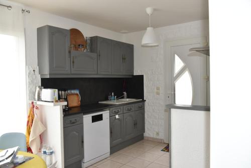 une cuisine avec des armoires grises et un réfrigérateur blanc dans l'établissement Maison douillette à 600m de la plage, à Saint-Michel-Chef-Chef