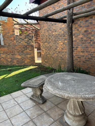 a stone bench sitting next to a brick building at Martinique Lodge in Alberton