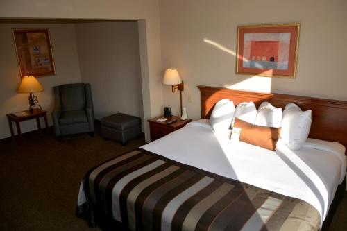 a hotel room with a bed and a chair at Wingate by Wyndham West Monroe in West Monroe